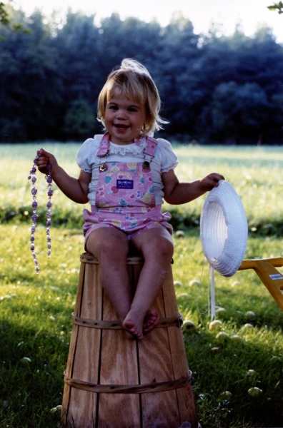 Childhood photo of BrandFuel employee Bridget Ray holding a hat and necklace.