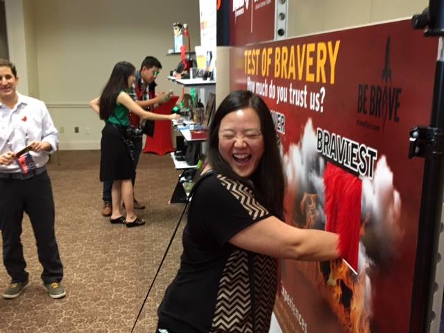 A woman reacting with joy to her hand being in the "Test of Bravery" machine.
