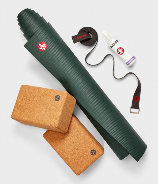 A rolled up yoga mat, blocks, strap, and cleaning spray.